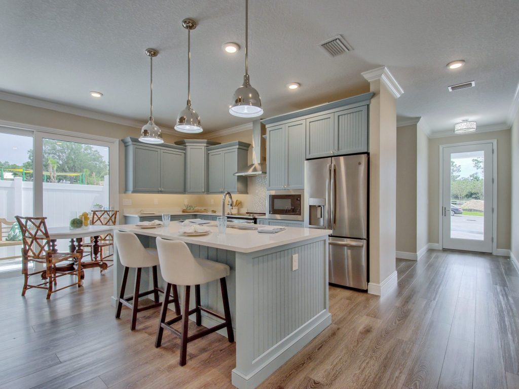 Mangrove model kitchen with blue cabinets, white island, stainless steel appliances, and wood-look flooring.