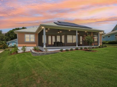 Homes with no electric bill Florida - a Green Key Village solar-powered home with screened porch and rooftop panels at sunset