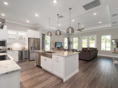 Open concept kitchen with white cabinets, granite counters, stainless appliances, and island with pendant lights.