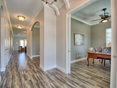 Elegant hallway with arched doorways and dark wood flooring leading to a formal dining room.